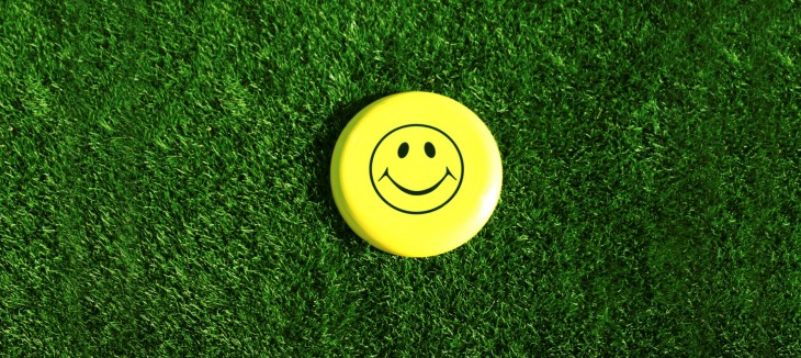 A Happy Face sits in the middle of a grass lawn in the summer