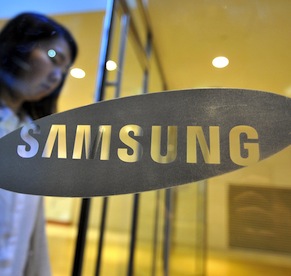 A woman walks past a logo of Samsung Ele