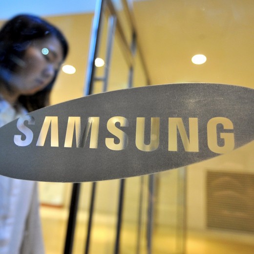 A woman walks past a logo of Samsung Ele