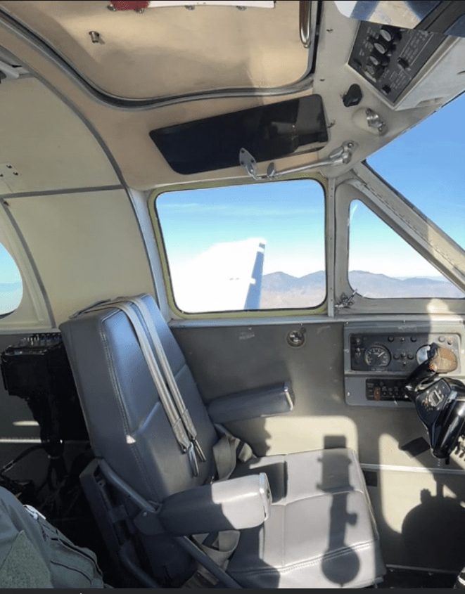 The cockpit of a King Air aircraft in flight with an empty pilot's seat