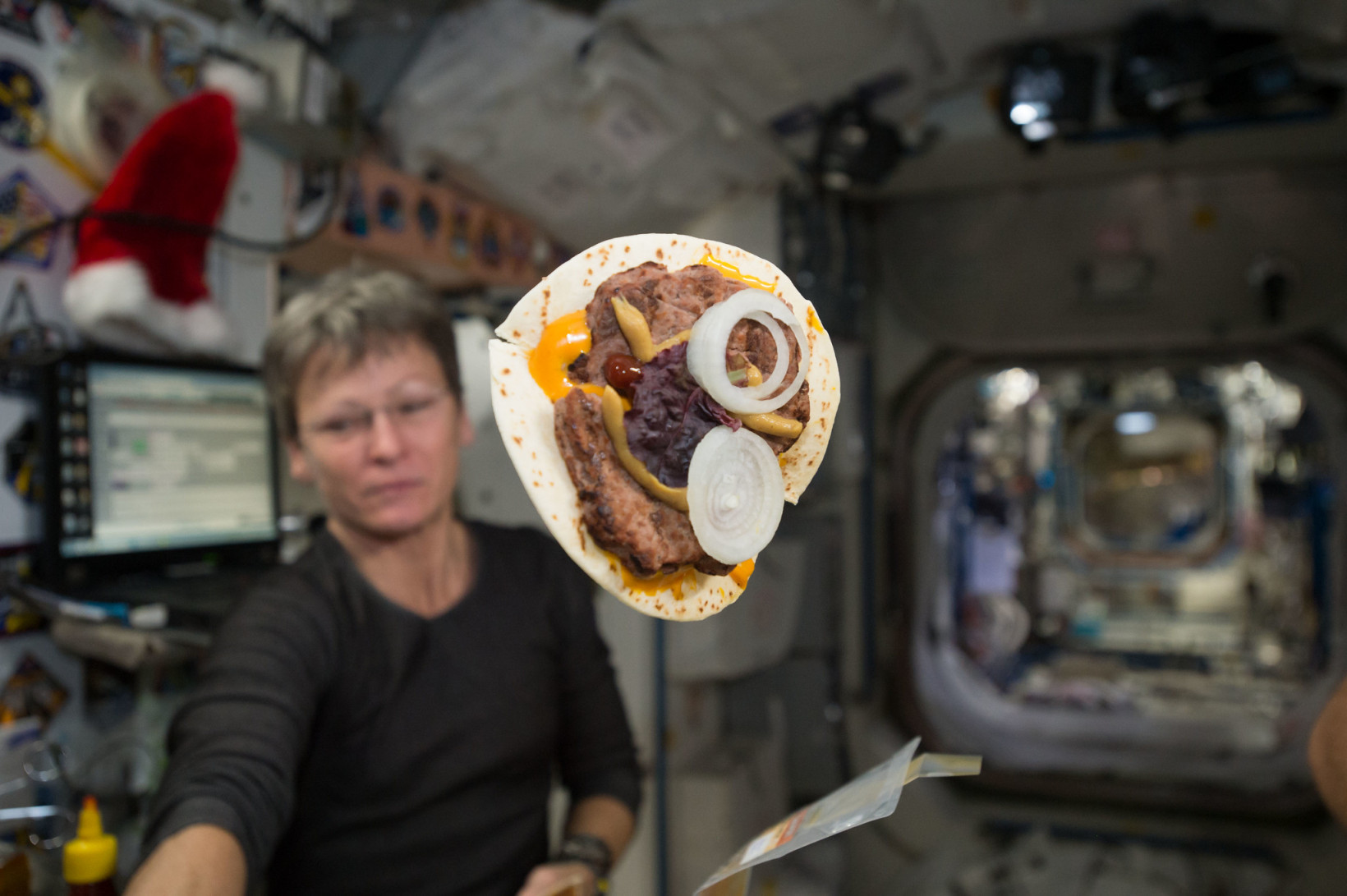A "space cheeseburger" is seen floating inside the International Space Station with Expedition 50 flight engineer Peggy Whitson of NASA in the background