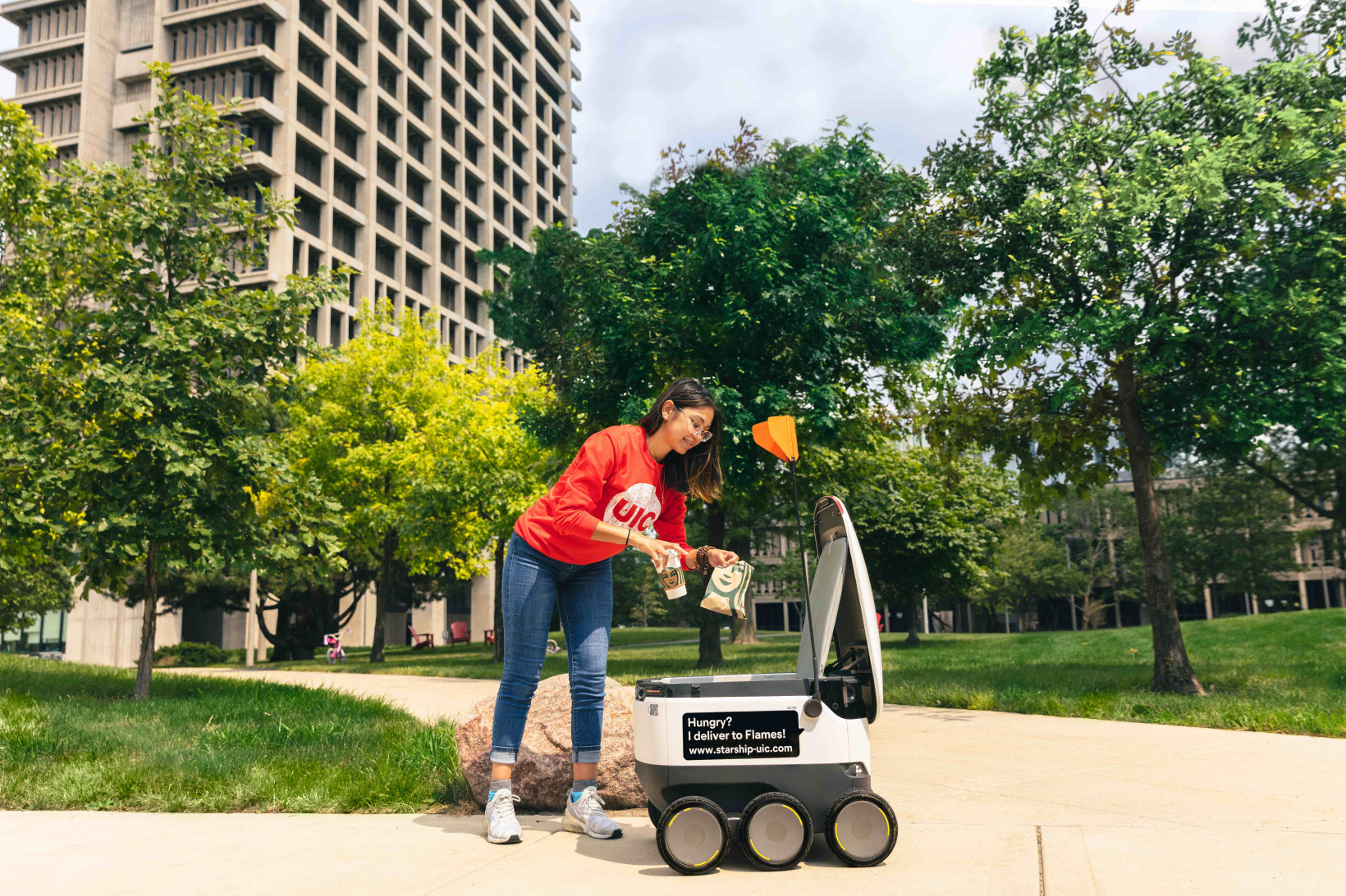 Girl picking up delivery from Starship technologies robot 