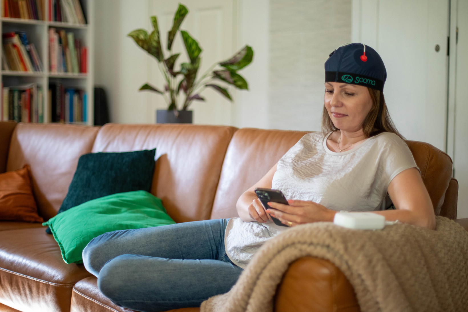 A woman sitting on a sofa wearing a brain stimulator